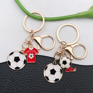 Close-up of golden soccer keychains with enamel jersey and cleat charms on leather