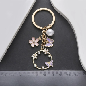 Vue détaillée de breloques cerisier et papillon avec perle sur un porte-clés doré
