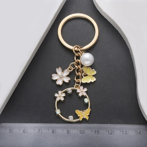 Detailed view of butterfly and flower keychain with pearl and yellow enamel charms