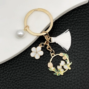 Portachiavi gatto con perla, fiore in smalto bianco e nappa su anello dorato