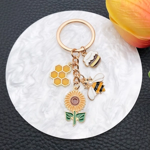 Detail of bee, honeycomb, sunflower, and cupcake charms on a golden metal keychain
