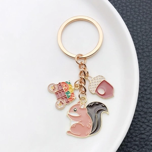 Detail of enamel squirrel and pumpkin carriage charms on a rose gold keychain