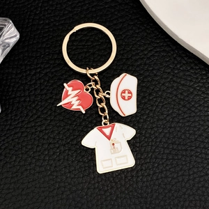 Detailed macro of gold metal keychain with medical charms, heart and nurse cap on leather
