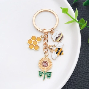 Close-up of golden sunflower bee honeycomb keychain charms with enamel drip finish