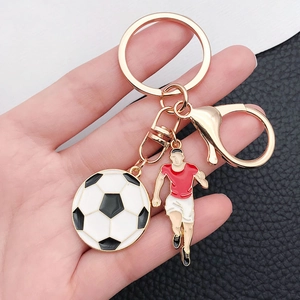 Golden football keychain with enamel soccer ball and red jersey athlete pendant