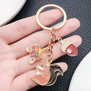 Detail of rose gold squirrel and acorn enamel pendants on a harvest keychain charm