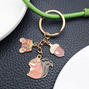 Squirrel and acorn enamel keychain with a decorative carriage on a black leather background