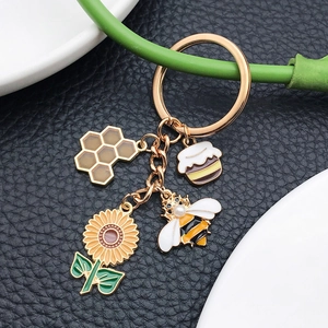 Bee and sunflower keychain with honey pot and beehive charms on black leather background