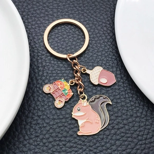 Detail view of squirrel, acorn, and harvest cart pendants on a rose gold keychain