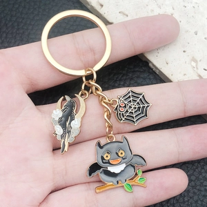 Porte-clés Halloween avec pendentif chauve-souris dorée et toile d'araignée sur main
