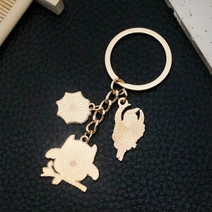 Détail d'un porte-clés en métal doré avec breloques cygne et parasol sur cuir