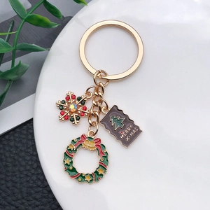 Détail d'un porte-clés de Noël doré avec flocon, couronne et breloque Merry X-MAS sur assiette