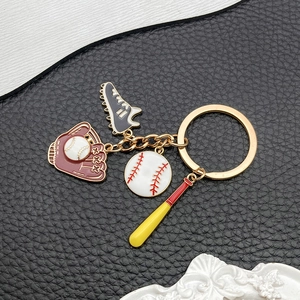 Detailed view of enamel baseball glove, bat, and sneaker charms on golden metal keychain