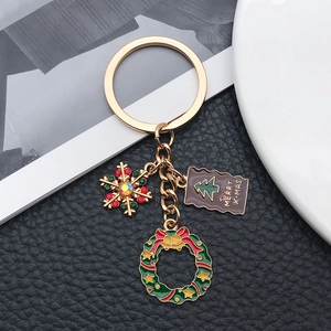 Détail de porte-clés de Noël doré avec flocon en strass, couronne et étiquette X-mas
