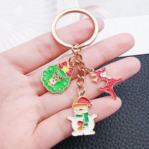 Detail of Christmas keychain with enamel charms featuring reindeer, snowman and rose gold chain