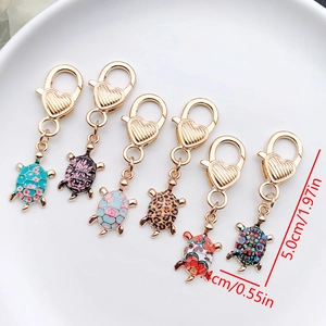 Detail view of six turtle charms with colorful patterns and heart-shaped lobster clasps