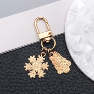 Detail of golden metal keychain featuring snowflake and textured bear pendants with lobster clasp