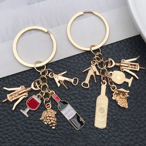 Detailed view of gold wine themed keychains with Lafite bottle and grape charms