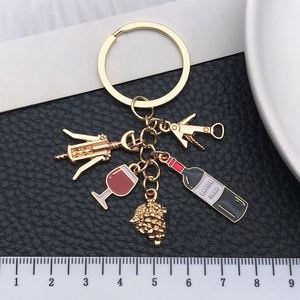 Detail view of gold wine lover keychain with mini corkscrew and charms next to a ruler
