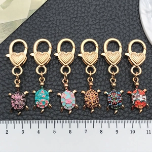 Set of 6 colorful turtle keychains with heart hooks and leopard print shells next to ruler