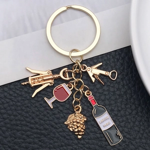 Detailed close-up of a gold wine-themed keychain featuring 1982 wine bottle and grape charms