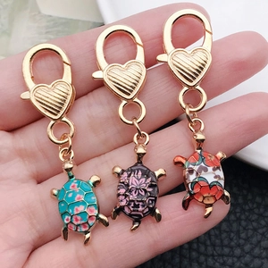 Detailed close-up of three colorful turtle keychains with heart-shaped clasps in hand