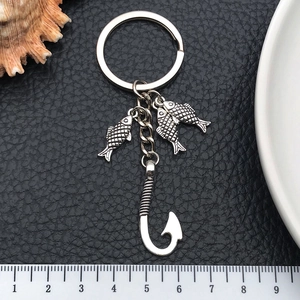 Detail shot of antique silver fish hook and small fish pendants with ruler on leather