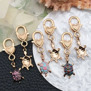 Detail view of six cute turtle keychain charms with heart lobster clasps on textured background