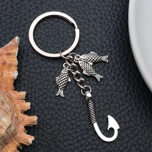Detail of antique silver fishing hook keychain with three small fish on black leather