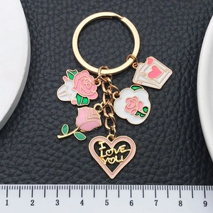 Schlüsselanhänger mit rosa Rosen, Herzanhänger und Herz-Ass-Karte auf schwarzem Lederhintergrund