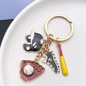Detailed close-up of baseball keychain with golden ring and four sports charms on white disc