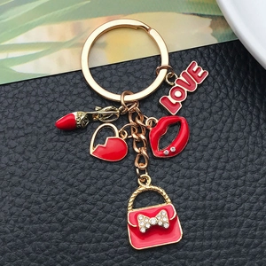 Dettaglio di ciondoli in smalto rosso con labbra e cuore su un portachiavi dorato lucido