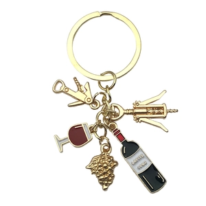 Gold wine themed keychain with corkscrew, grape, and red wine bottle charms on white background