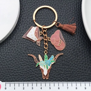 Cowboy themed keychain with brown enamel hat bull skull and tassel on gold chain