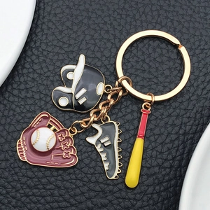 Detailed macro view of enamel baseball glove, helmet, shoe and bat charms on golden keychain
