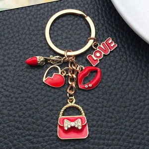 Dettaglio dei ciondoli a labbra rosse e borsa su un portachiavi dorato su pelle nera