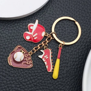 Detail of red baseball hat glove and bat charms on a golden keychain over black leather