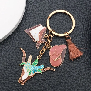 Detail of western keychain with cow skull, pink cowboy hat, and brown tassel on leather