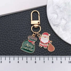 Porte-clés de Noël avec Père Noël et sac cadeau en émail sur fond noir avec un mousqueton doré