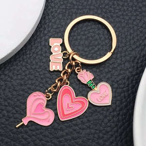 Detail of pink heart rose charms with LOVE tag on gold metal keychain with black background