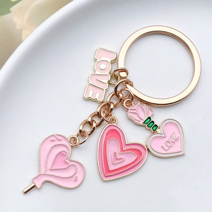 Detail of pink enamel heart and rose charms with LOVE engraving on a gold keychain