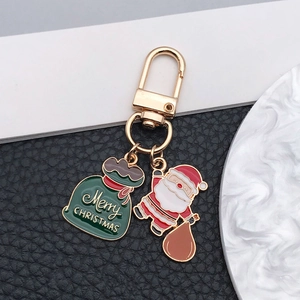 Détail du Père Noël en émail et du sac cadeau vert sur un porte-clés doré festif