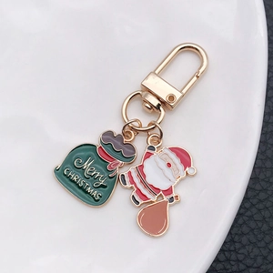 Porte-clés Père Noël et sac cadeau en émail avec placage doré sur une assiette blanche