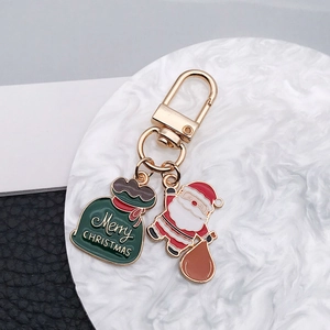 Détail de breloques de Noël Père Noël et sac cadeau en émail sur un porte-clés doré