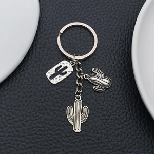 Antique silver cactus keychain with hollow metal charms on black leather texture