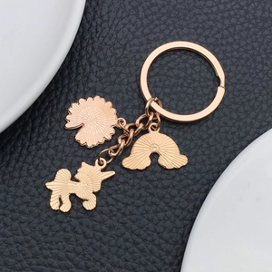 Detail of rose gold keychain with unicorn, rainbow, and flower charms on leather