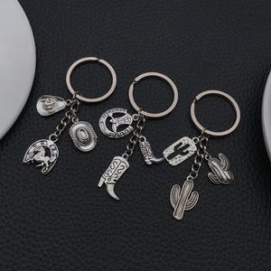 Western style horse boots and cactus alloy keychain set on black leather background