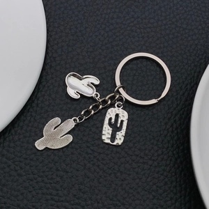 Macro detail of three silver cactus charms with textured alloy finishes on key ring