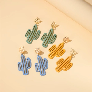 Three pairs of cactus pendant earrings in green, light blue, and yellow with gold studs