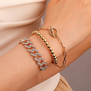 Close-up of gold-tone layered bracelet set with Cuban link, bead chain and toggle clasp